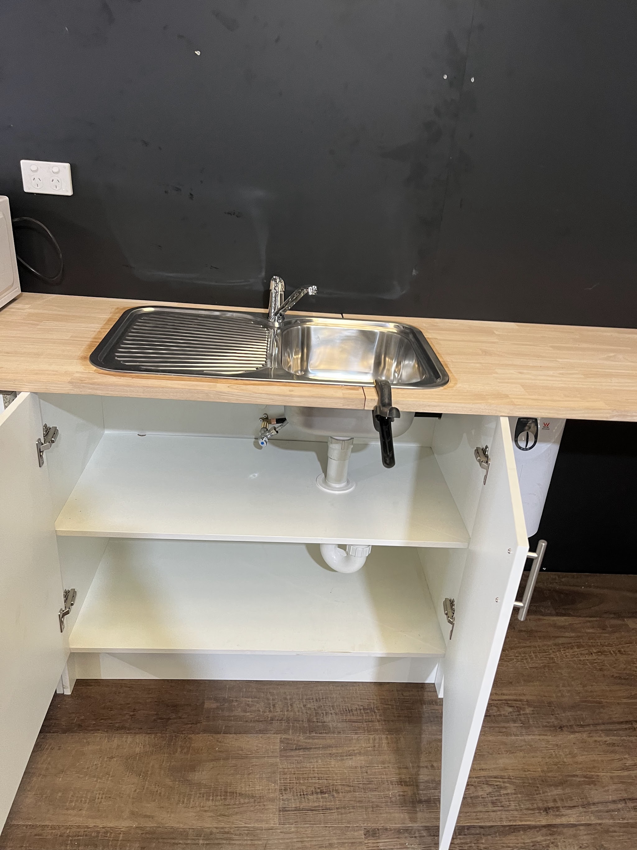 New stainless steel sink and mixer set into a timber benchtop with tidy waste below