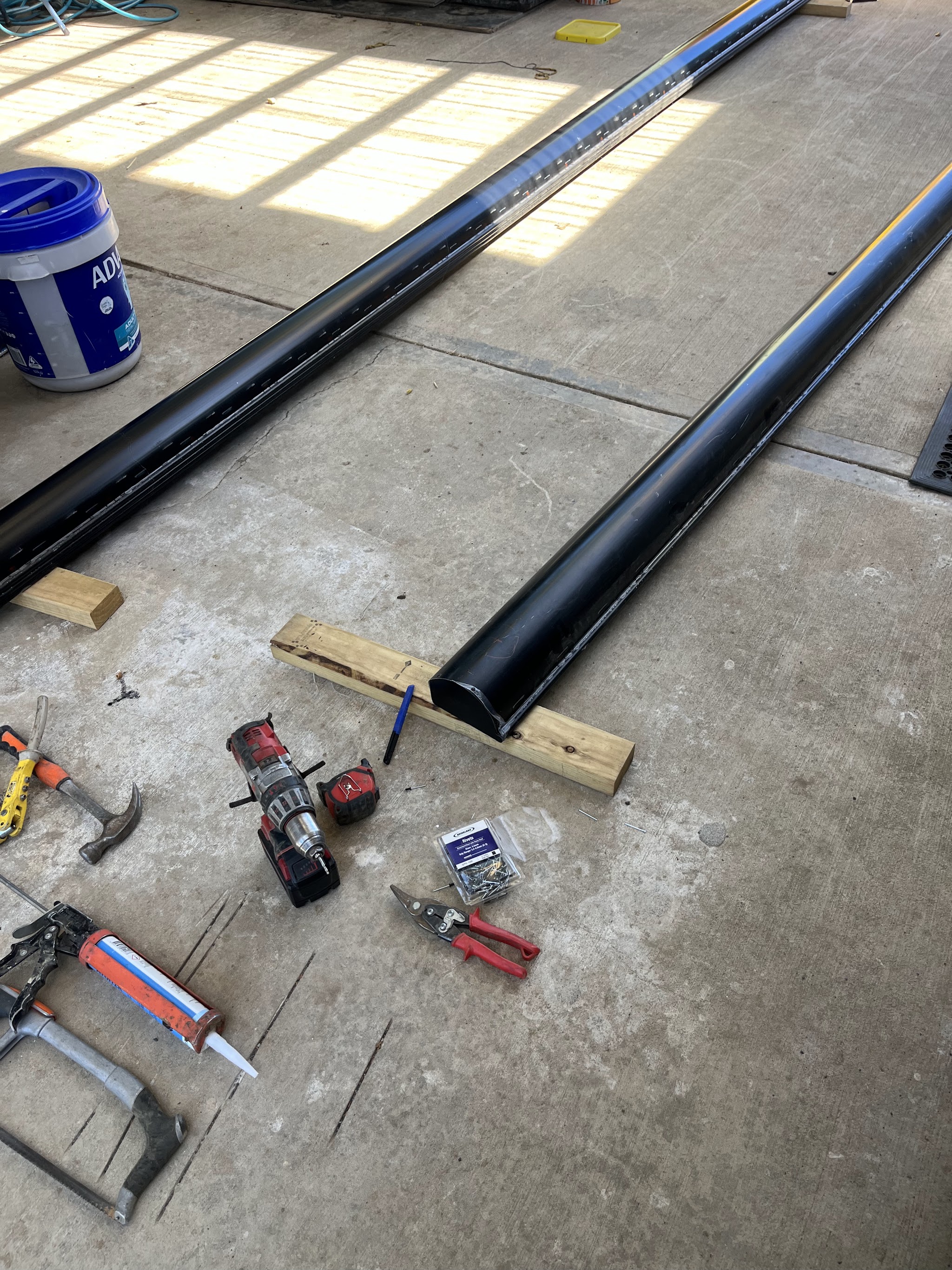 New black Colorbond guttering and downpipe stock laid out in a shed ready to be cut