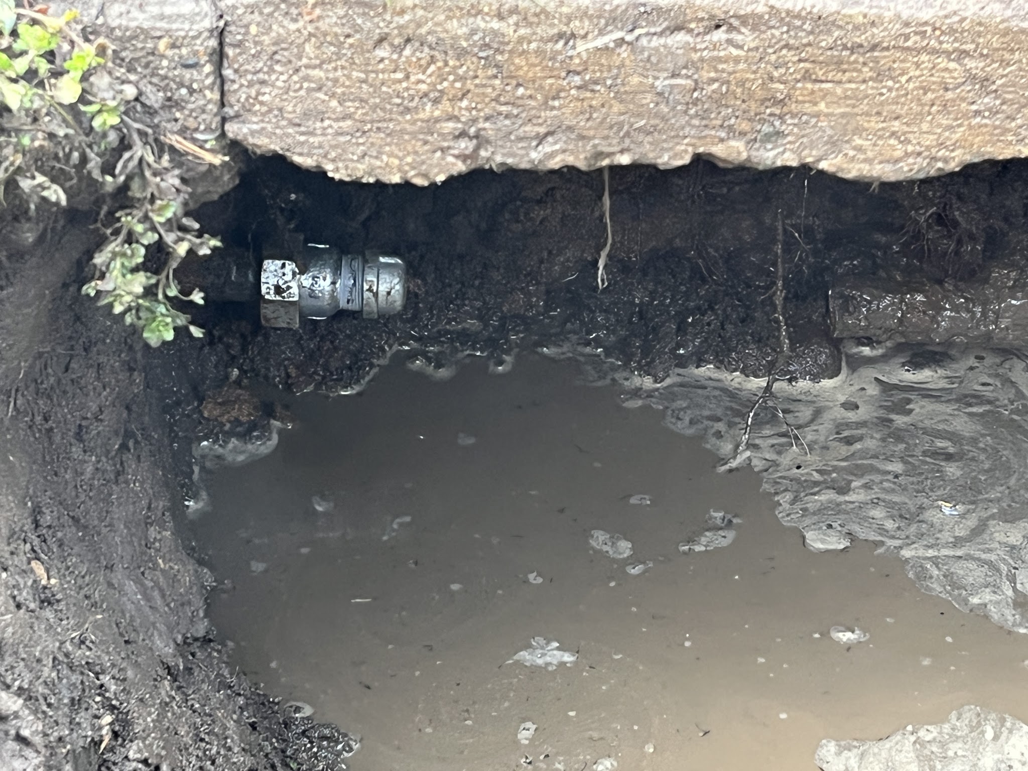 Excavated water service under a concrete slab edge with a compression coupling fitted on the pipe